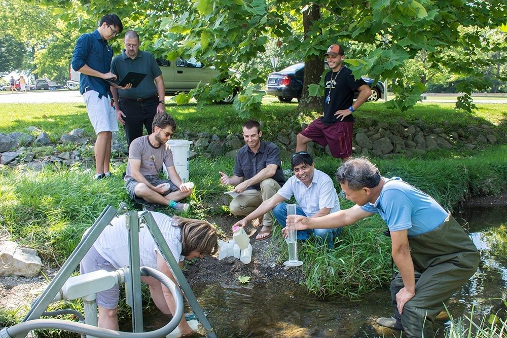 Vinod Lohani, a professor of engineering education, directs a Research Experiences for Teachers site focusing on interdisciplinary water research. Here, Lohani, center, works with local teachers and Virginia Tech researchers to collect water samples at his lab's Stroubles Creek field site.