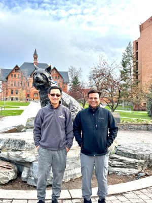 Weinan Leng and Bipin Lade pose with a bronze sculpture of Montana State's first bobcat, the centerpiece of Alumni Plaza on MSU's campus, MONT